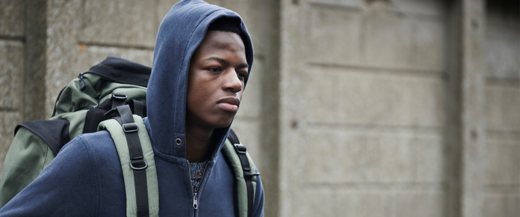 Young man in a hoodie looking thoughtfully outdoors.